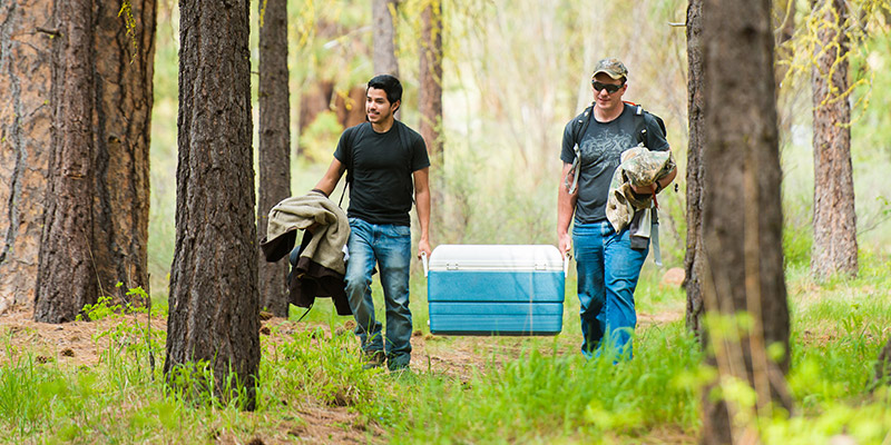 Two students carry a cooler.